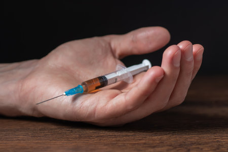 Addict man dead after inject drug overdose with syringe injection heroin to hand. Social disaster and epidemic of narcotic addiction conceptの写真素材