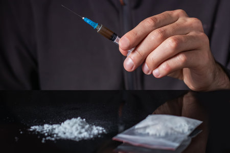 Drug syringe in hand. A drug addict with another dose of the drug in the syringe. Guy addicted, The...