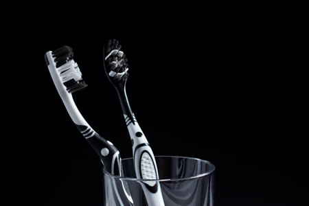 Two toothbrushes in a glass with copy space on black.の写真素材