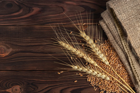 Ears of ripe wheat, scattered grains on a wooden board