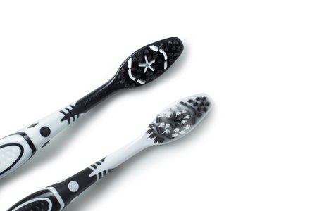 Two toothbrushes black and white color for dental care lies on the table on a white background.