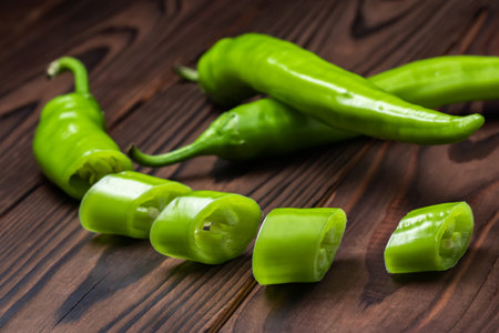Green hot chili peppers with slices on wooden background.の写真素材