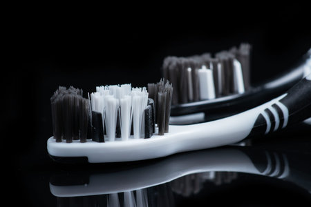Two toothbrushes black and white color for dental care lies on a black background.