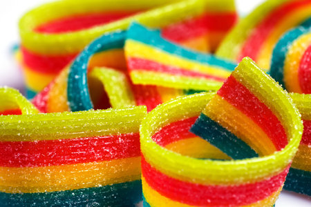 Colorful jelly candies strips in sugar sprinkles. Sour flavored rainbow candy background