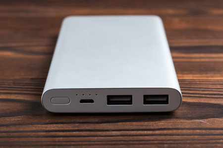 Power bank for charging mobile devices on wooden background. battery bank. External battery for...