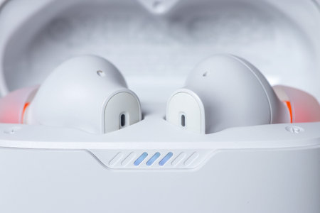 Two white wireless headphones in a case on a white background,