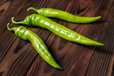 Group of green bitter peppers on wooden background.