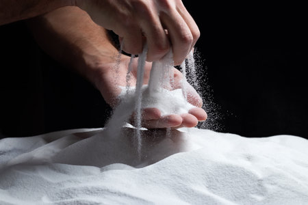 Sand through fingers on black background. Concept of the flow of life..の写真素材