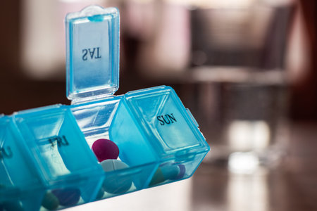 Pill organizer with variety of pills and supplement. Weekly Pill Organizer on the table. Daily pill...
