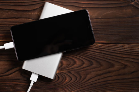 Powerbank and charge smartphone on wooden table.の写真素材
