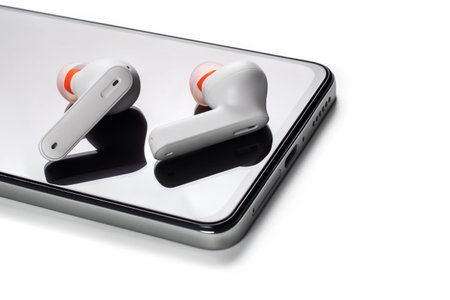 Wirelsss white headphones and smartphone on white background.