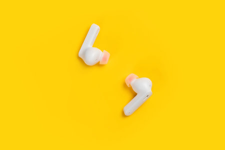 Wireless Earphones. Earbuds or headphones on yellow background.