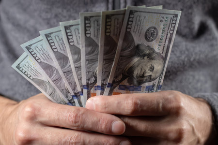 Men's hand holds a fan of dollars close up.