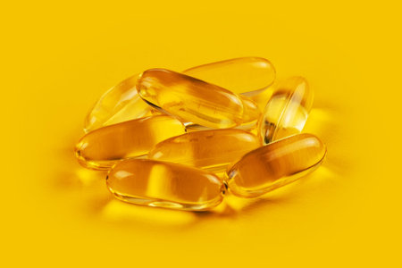Fish oil capsules with omega 3 and vitamin D on yellow background.