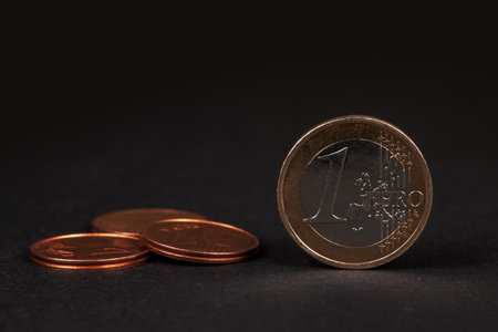 One Euro coin on black background, with many coins blurred in the backgroundの写真素材