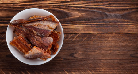 Pieces of cleaned dried fish isolated on wooden background. Dry Peppered Pollack. Amber with pepper.の写真素材