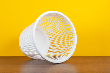 Empty overturned can trash, clean garbage bin, plastic basket bin on yellow background.