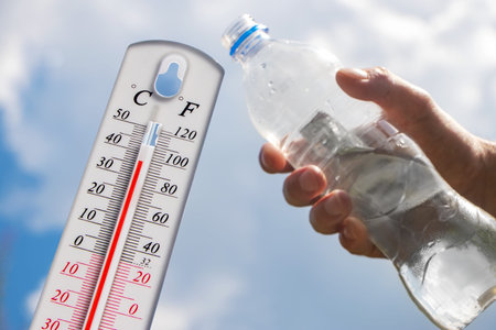 hot temperature,Thermometer and water bottle on sky with sun shining in summer show higher Weather,...