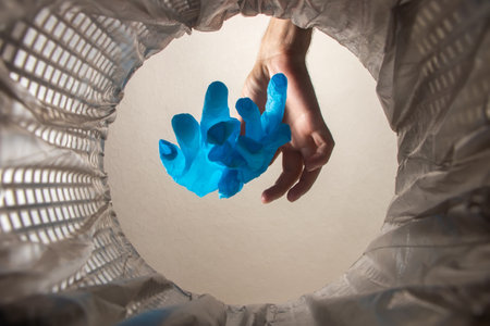 healthcare professional throwing away blue disposable latex gloves in trash. Infection control protocol. inside view.の写真素材