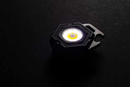 LED Flashlight Keychain and a beam of light in darkness. A modern led lamp with bright projection on dark tableの写真素材