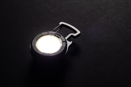 LED Flashlight Keychain and a beam of light in darkness. A modern led lamp with bright projection on dark tableの写真素材