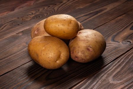 Fresh harvested potatoes on a rough wooden surface.の写真素材