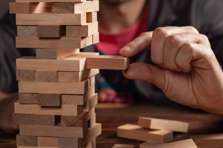 Closeup hand man take one block on The tower from wooden blocks.
