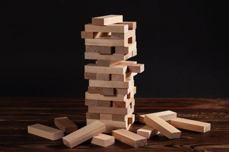 tower made of wooden blocks on dark background, space for text.
