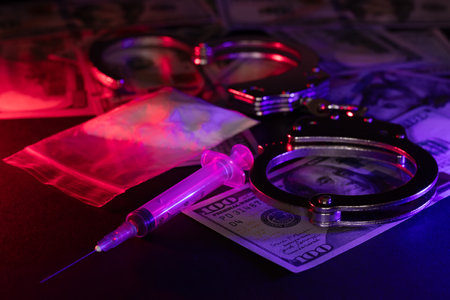 Handcuffs, drug syringe and drug powder and money.の写真素材
