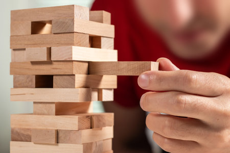 Close up hand man take one block on The tower from wooden blocks.の写真素材