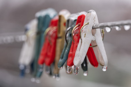 Frozen colorful clothes-pins in ice at winter morning.