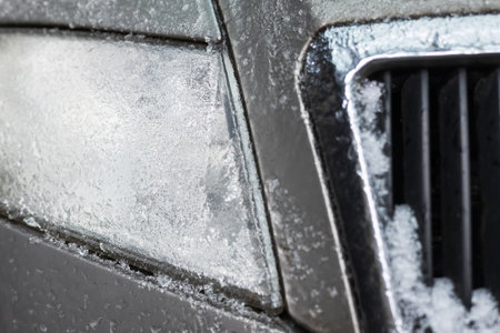 Frozen car headlights with icicles and snow in winter season, shows icy roads and snowy streets with dangerous weather and difficult traffic after snowstorm.の写真素材