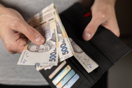 Banknote of 500 hryvnias in male hand close up. Gray wallet with Ukrainian money and credit cards on the background.の写真素材