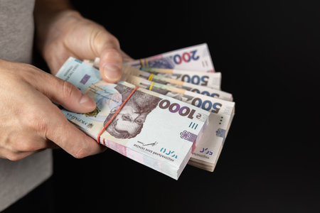 Men holding Ukrainian money on dark background, closeup.の写真素材