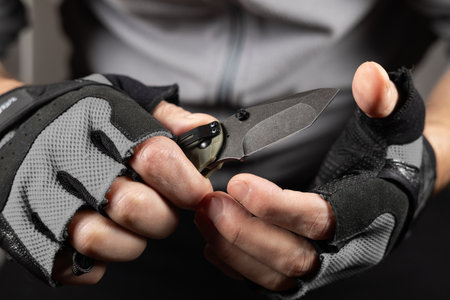 Hand in tactical glove, holding folding knife, close up.の写真素材