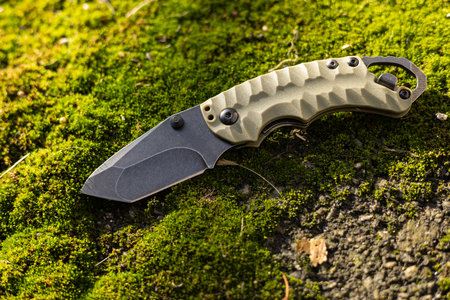 Tactical folding knife for survival on moss background.の写真素材