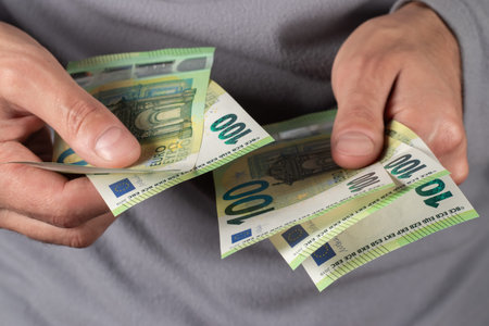 Men hold one hundred euro bill in his hands, pay with euros.