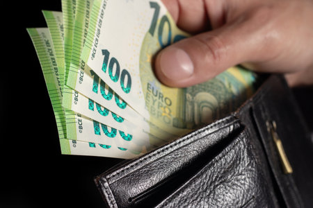 Wallet in hands full of 100 euro cash money banknotes. Close up view.の写真素材