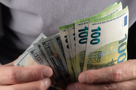 100 Euros and 100 dollars banknotes in men hands. Close up.の写真素材