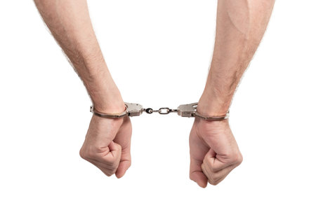 Arrested man handcuffed hands. Prisoner or arrested man, close-up of hands in handcuffs, selective focus. Isolated on a white background.の写真素材