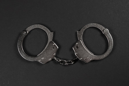 Shiny metal handcuffs on the dark table.の写真素材