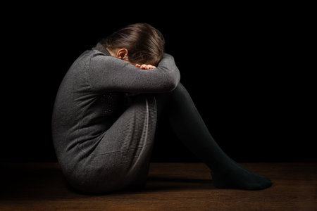 Domestic violence. Sad child sitting on floor in dark room.の写真素材