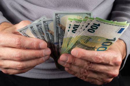 100 Euros and 100 dollars banknotes in men hands. Close up.の写真素材