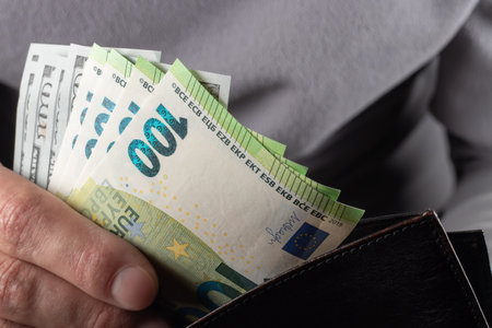 Man handing wallet with 100 euro and 100 dollars banknotes.の写真素材