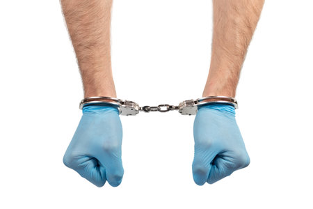 male hands in handcuffs and medical glove on white background, concept of medical corruption, bribery, crimeの写真素材
