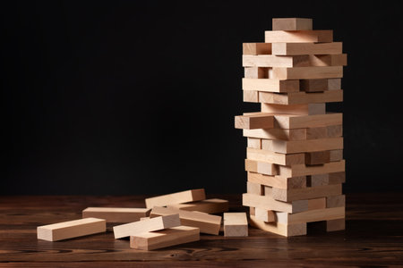 tower made of wooden blocks on dark background, space for text.の写真素材