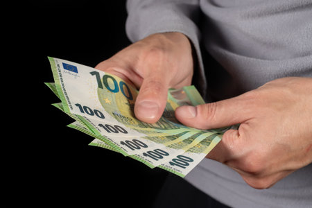 Men hold one hundred euro bill in his hands, pay with euros.の写真素材