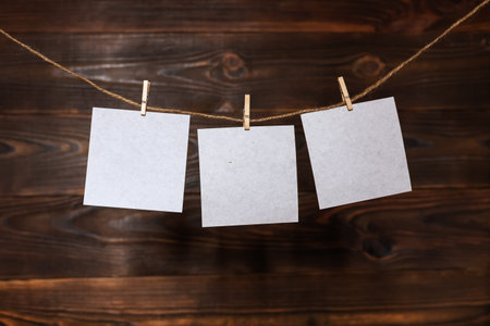3 Note paper cards hanging with wooden clip or clothespin on rope string peg on wooden background.の写真素材