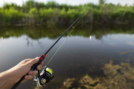 Closeup of a female hands holding a fishing rod and reel.の写真素材
