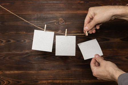 man hand take paper note cards hanging with wooden clip or clothespin on rope string peg on wooden background.の写真素材